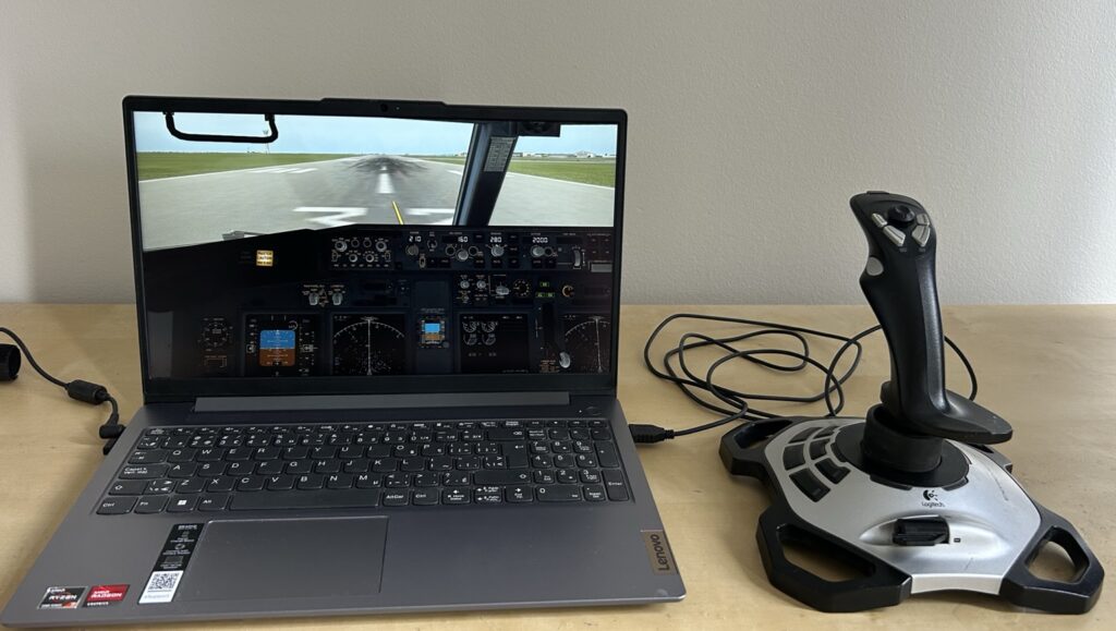 Budget flight simulator setup with Lenovo laptop running a Boeing 737 cockpit view and Logitech joystick controller.