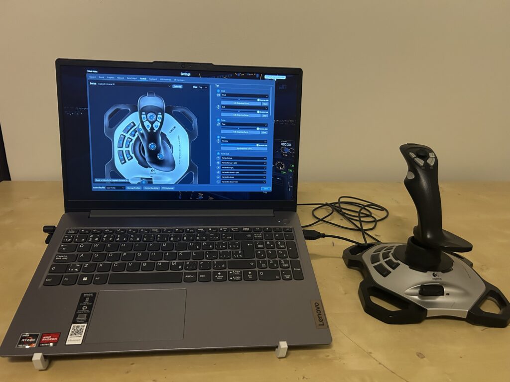 Lenovo laptop running X-Plane 11 with a Logitech Extreme 3D Pro joystick beside it