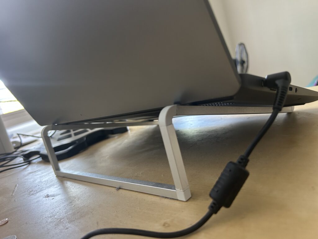 Side view of a Lenovo laptop raised above a desk on a laptop stand